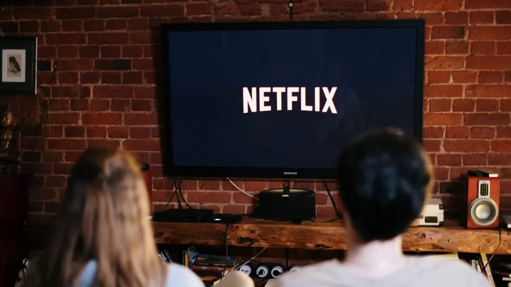 26 filmes que vão sair da Netflix em breve 2 um casal em frente uma televisão ligada escrita netflix