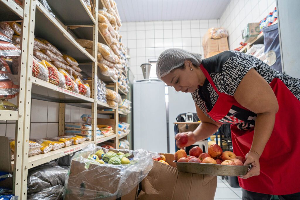 Uma mulher preparando a merenda dos alunos
