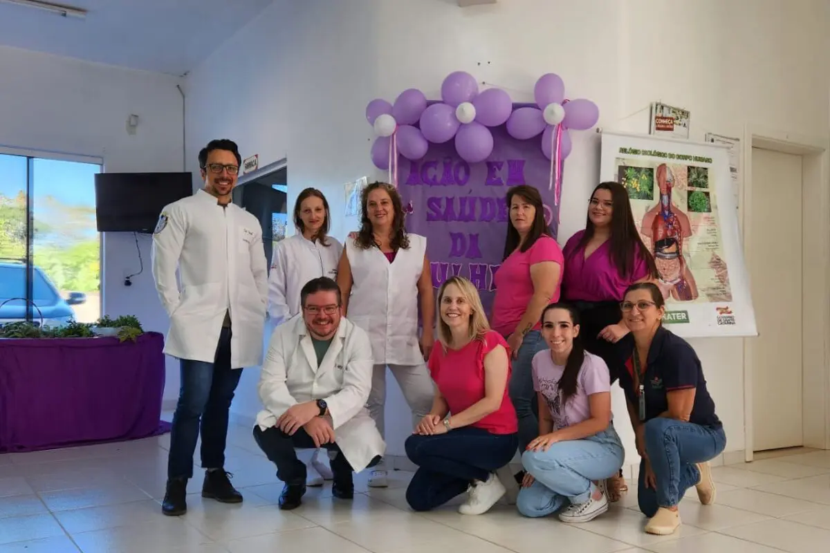 Equipe do ESF 5 juntos tirando foto com um cartaz escrito " ação em saúde da mulher "
