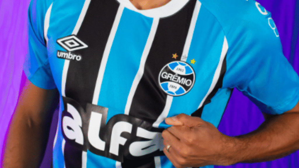 Grêmio pode ter novo fornecedor de uniformes em 2026 2 A partir de janeiro de 2026, o Grêmio deverá ter a New Balance como nova fornecedora de material esportivo.