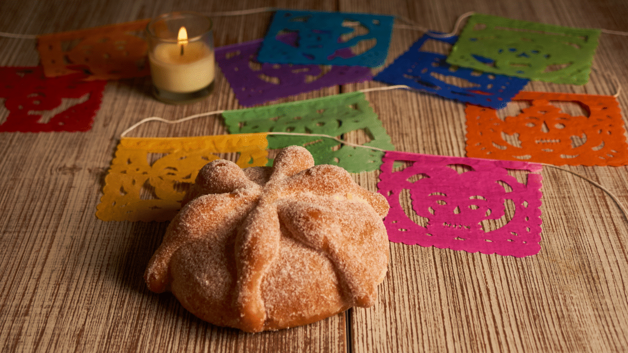 Entre caveiras e flores: Dia de los Muertos os segredos que encantam o mundo 4 pan de muerto, um pão doce decorado com tiras que simbolizam ossos e polvilhado com açúcar. Servido com chocolate quente, ele representa a comunhão entre vivos e mortos.