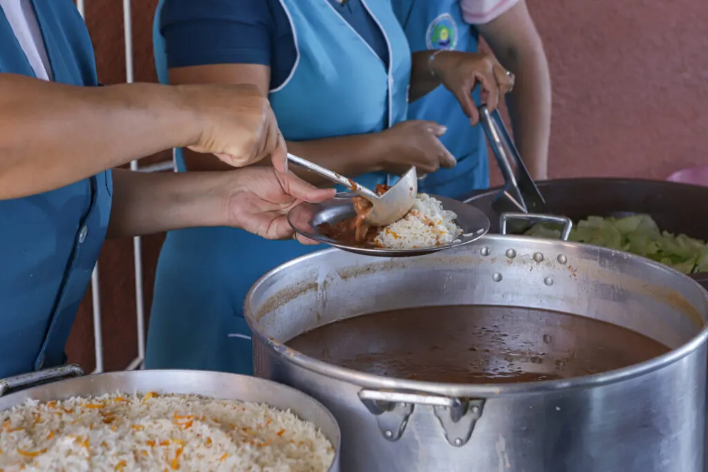 Na imagem esta mostrando 3 panelas de merenda escolar, uma de arroz, uma de feijão, e uma de alface